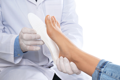 Osteopath fitting orthopedic insoles to patient